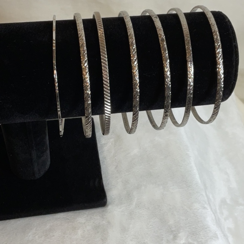 Thin metal bangle bracelets. Set of seven. Each carved with a different design.